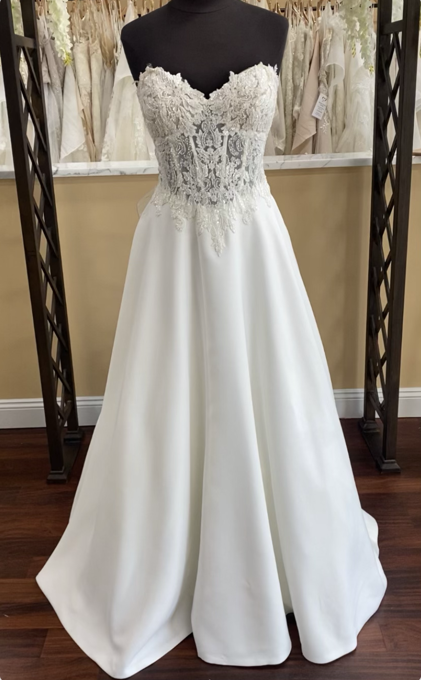 Lace and satin wedding dress on mannequin with sweetheart neckline and exposed boning in bodice with lace overlay, connecting to an align satin plain skirt