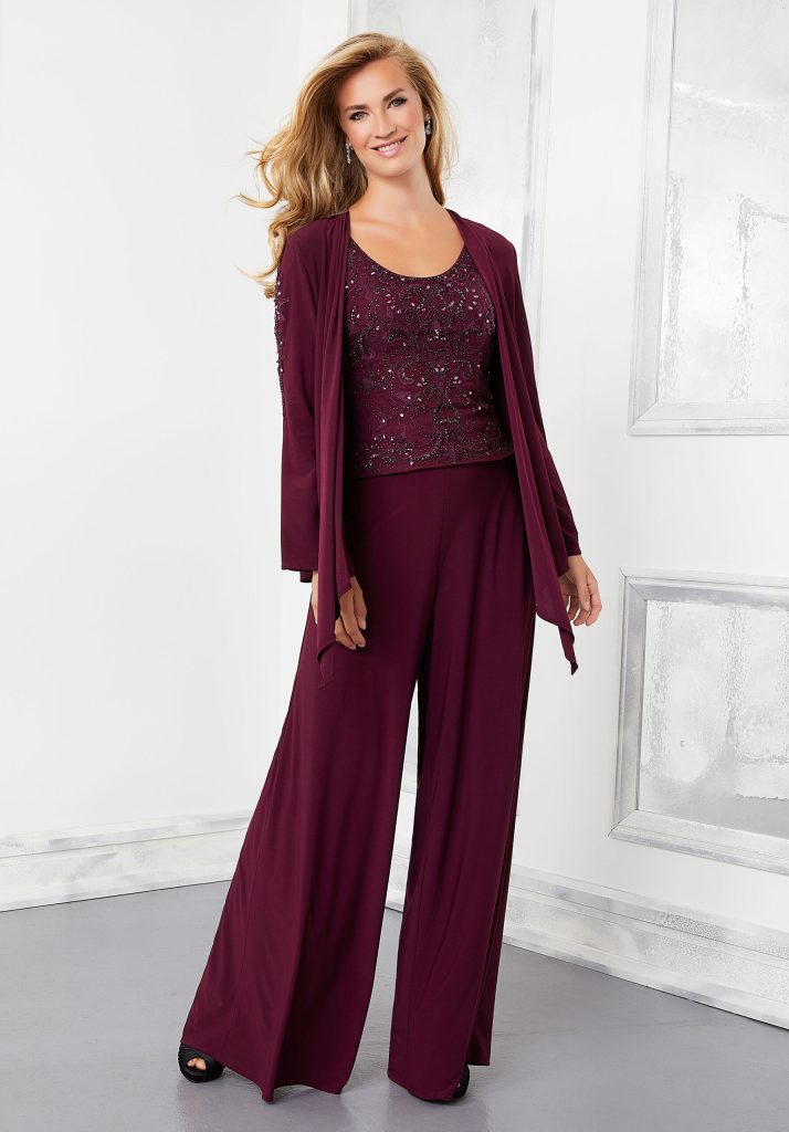 A three-piece women's pants suit in the color wine on a model including chiffon pants, beaded tank top, and matching chiffon long sleeve buttonless jacket
