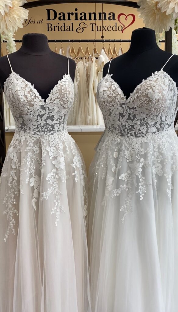 Two lace wedding dresses on different size mannequins, one in size 10 in champagne with Ivory lace, the other in size 24 in all ivory. Both with spaghetti straps, sweetheart neckline, illusion bodice, and a line shape.