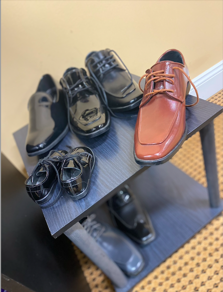 Tuxedo shoes in black brown and gray displayed for customers in sizes for adults as well as a pair of tiny black patent leather ring bearer shoes