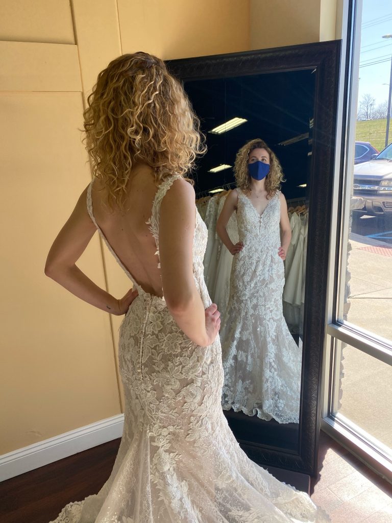 Bride in a full lace fit and flare V-neck dress with a low back having photo taken in the mirror