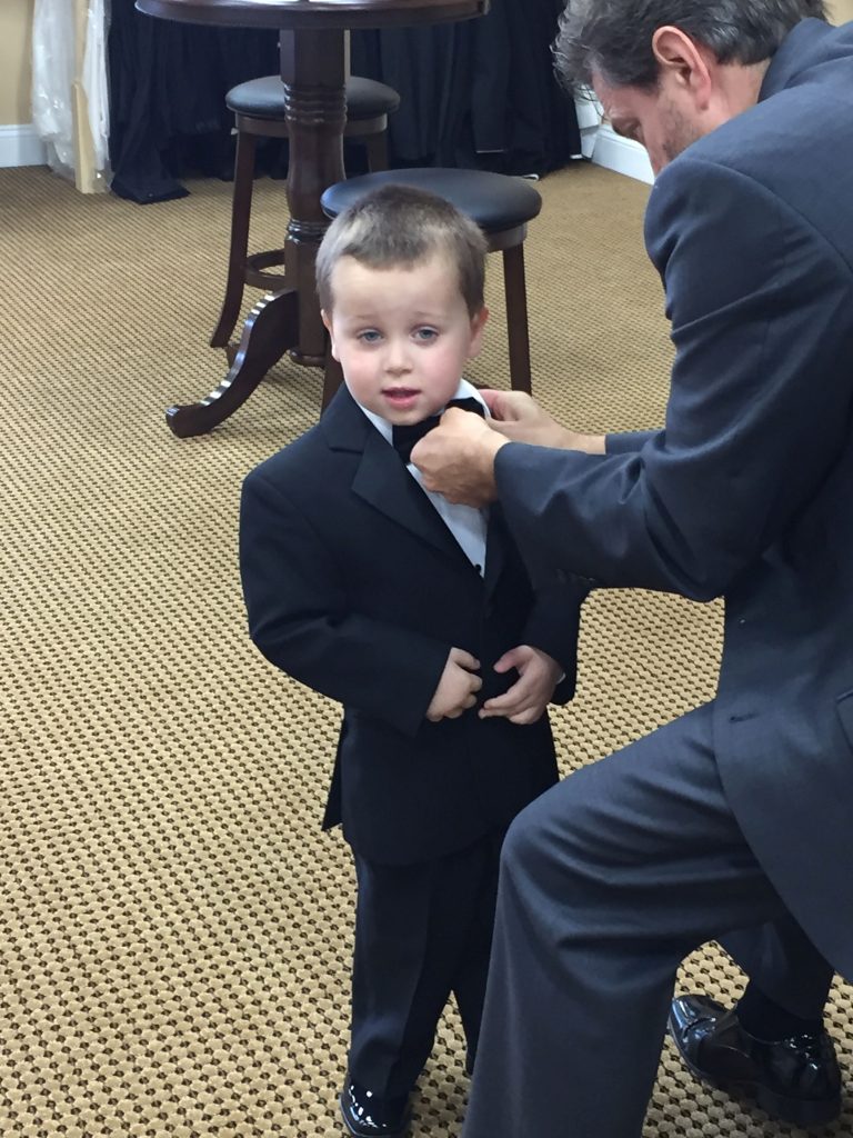 A ring bearer gets his bowtie adjusted at Darianna Bridal & Tuxedo