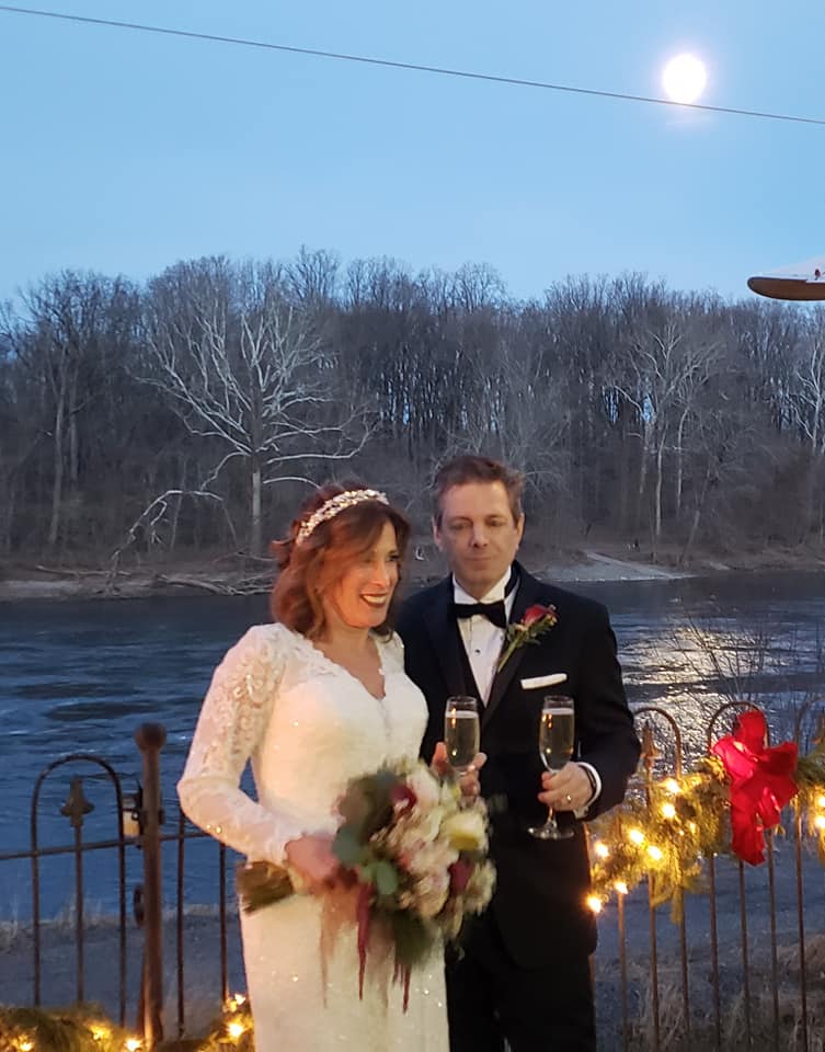Bride and groom with champagne after ceremony by the river with a full moon reflecting on the water