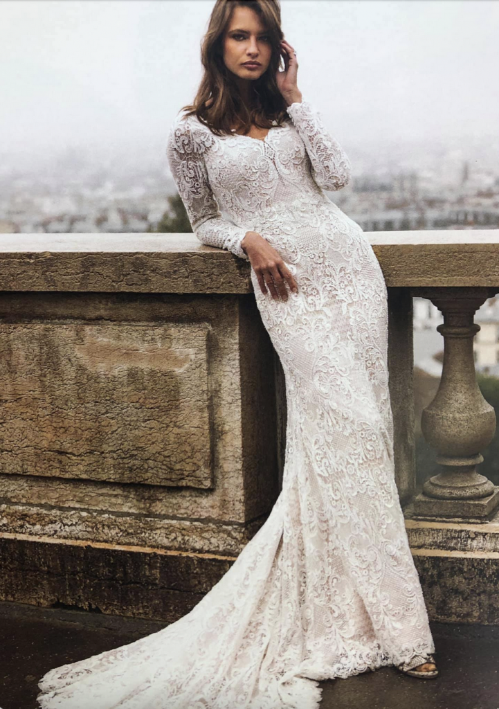 Madi Lane Izadore wedding dress with layers of shimmery lace, a conservative plunge neckline, illusion back, and long sleeves