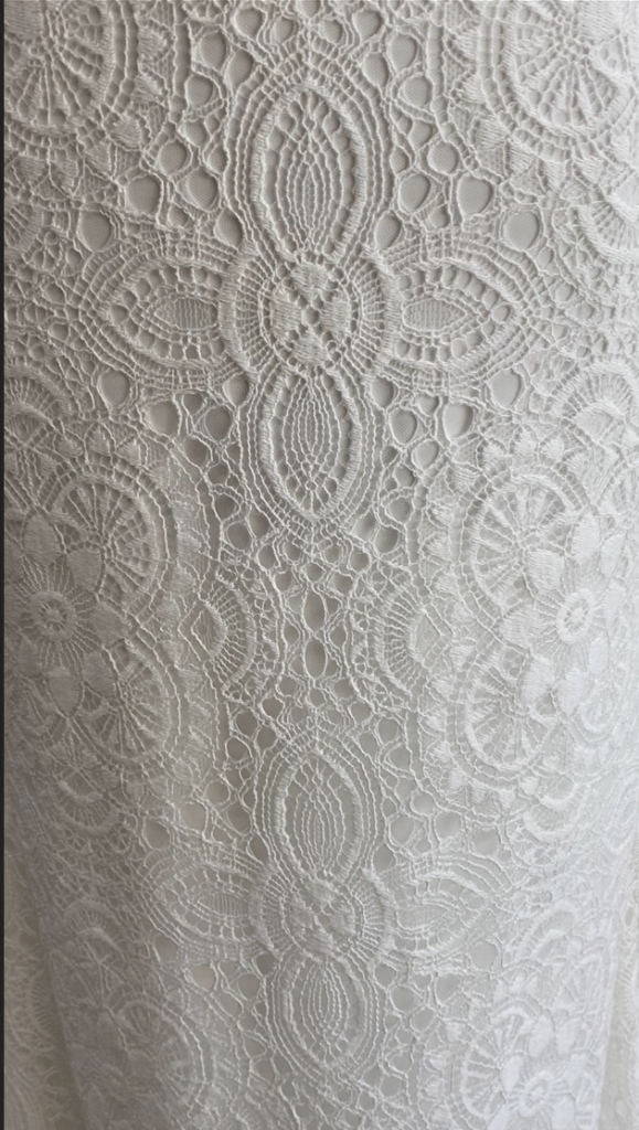 Intricate geometrical patterned lace over a charmeuse layer