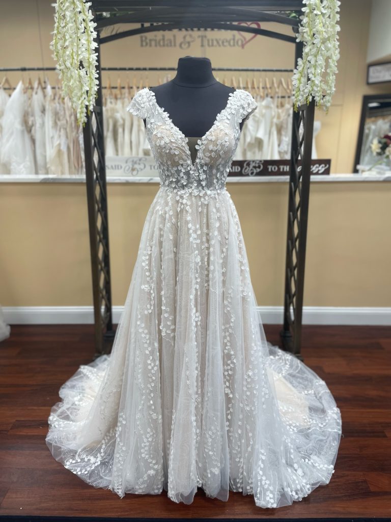 Verona by Mia Solano is a beautiful A-line wedding dress with cap sleeves, plunge neckline, and lovely 3D shimmery vine lace
