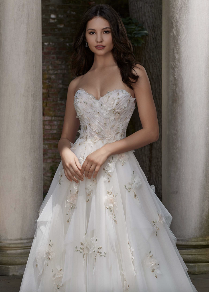 Model in a strapless A-line wedding dress with blush pink and sage green flowers and embroidery. Petal dress by Morilee