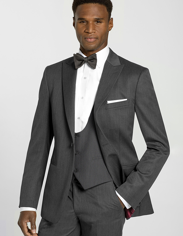 Steel grey Dylan suit. On model with scoop vest, open jacket with peak lapel, white dress shirt, gray bowtie, white pocket square.