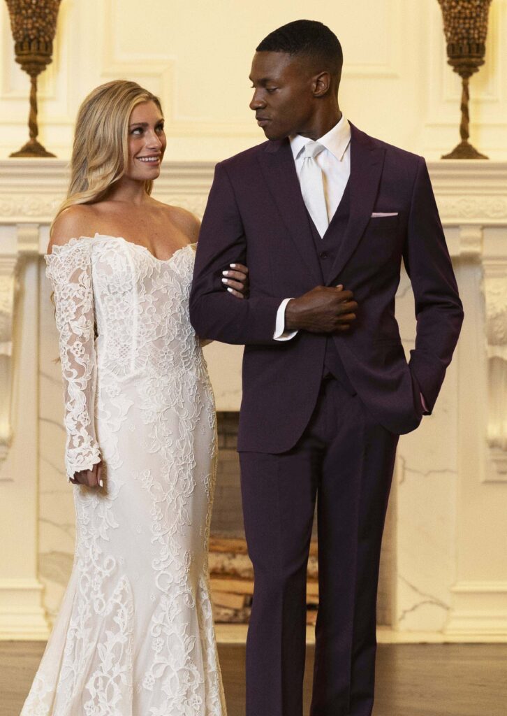 Bride and groom models, groom in in a dark purple suit with a matching vest and pants, ivory tie, white shirt and light pink pocket square pocket square