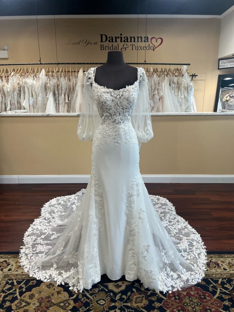 Crêpe and lace wedding dress, off the shoulder bishop sleeve. Beaded lace straps, scoop neckline, lace illusion bodice. Lace continues over hips and down sides of skirt leading to a fully illusion lace scalloped cathedral train.