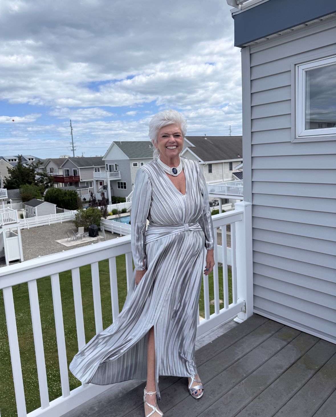 Woman wearing custom made a silver striped formal dress during a custom dress fitting on an outdoor balcony