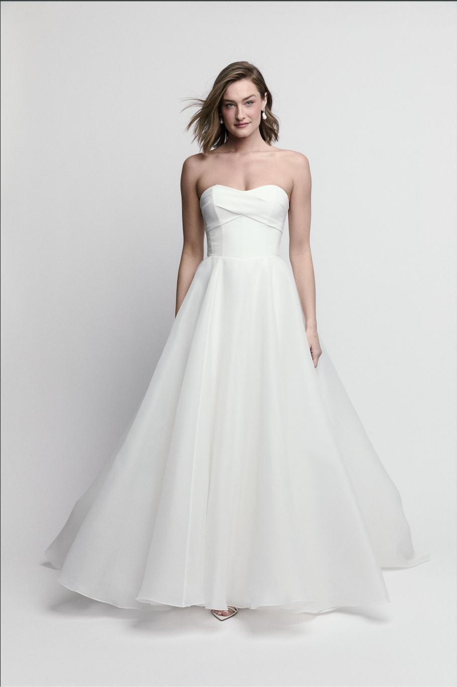 Bride modeling strapless A-line wedding dress with draped bodice and flowing ivory skirt